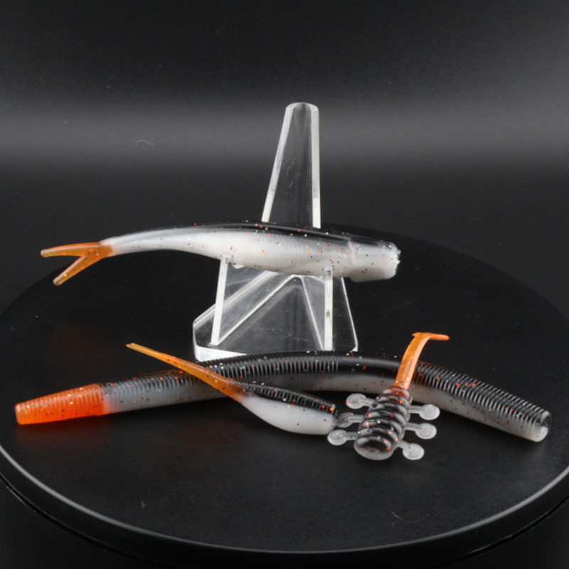 Fishing lure set: white speckled soft plastics with orange tails and ribbed bodies, in stand