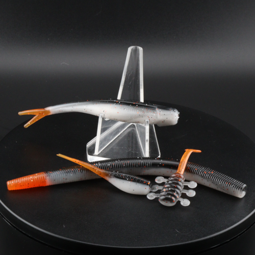 Fishing lure set: white speckled soft plastics with orange tails and ribbed bodies, in stand
