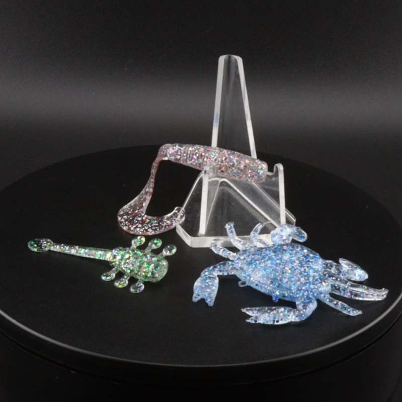 Glitter bomb fishing bait set with clear stand and pink and blue glitter lure pieces
