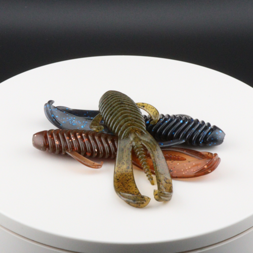 3.25-inch brown and green soft plastic creature lures, ribbed bodies, on white plate