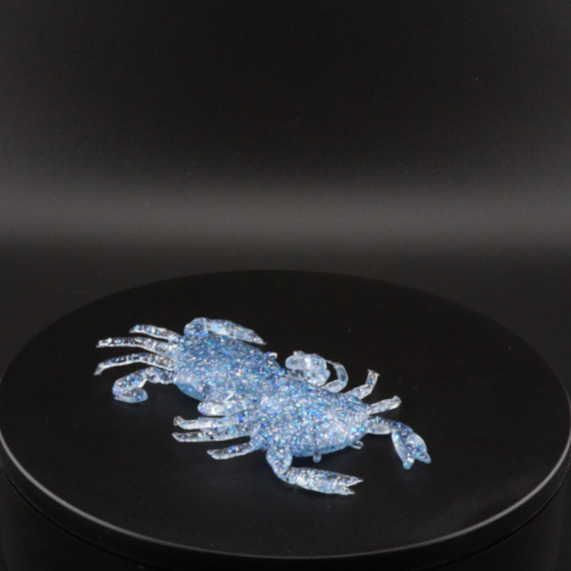 Blue glitter soft crab-style fishing bait on a round display stand