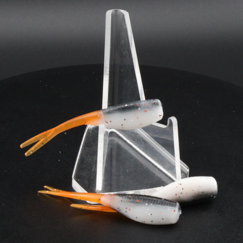 Fishing lure set with white speckled soft plastics, orange tails, in clear display stand
