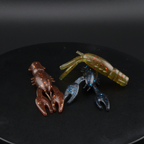Soft plastic craw lures in dark brown, green, and blue, with clawed legs