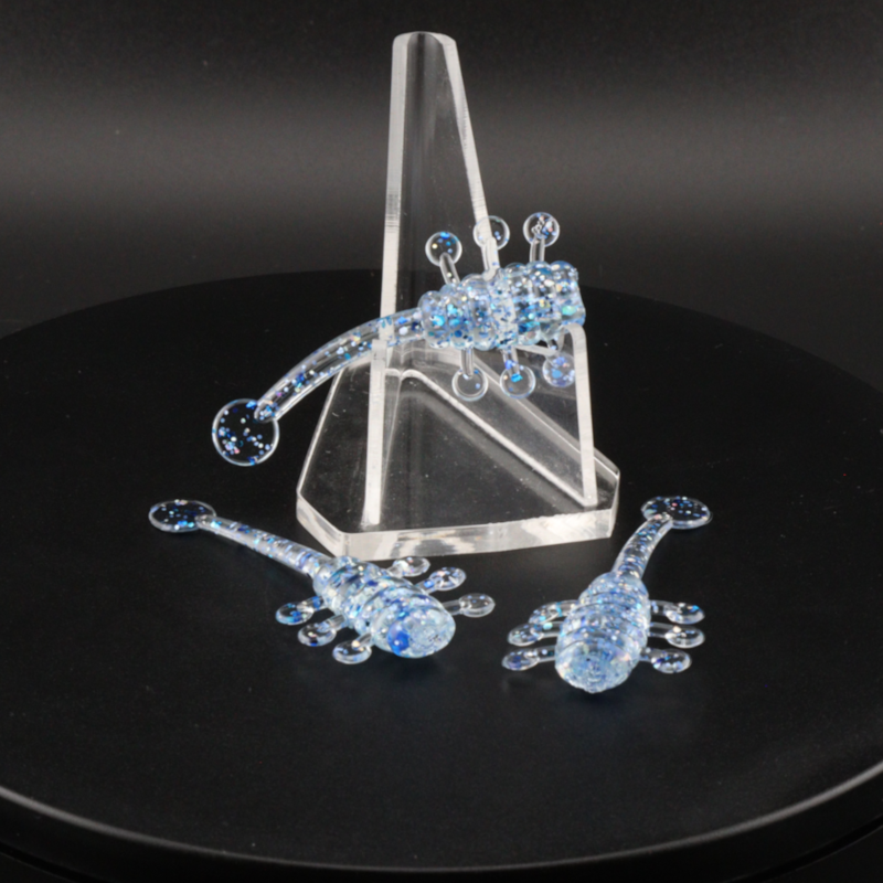 Glitter fishing bait with blue sparkly lure pieces and treble hooks on clear stand